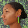 Woman wearing colorful earrings with a leafy green background