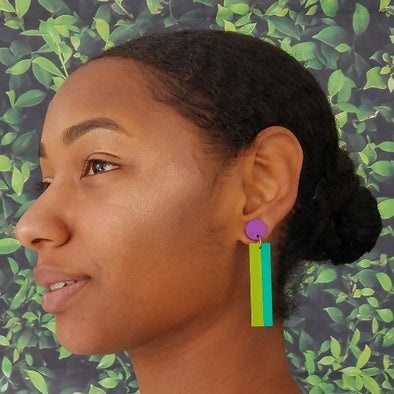 Woman wearing colorful earrings with a leafy green background