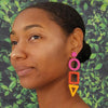 Woman wearing colorful earrings with a green leafy background